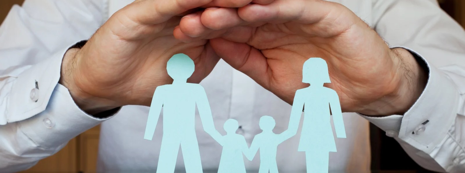 two hands over paper family cut-outs