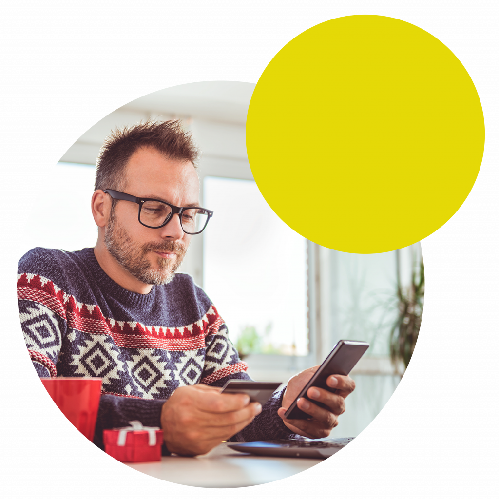 men wearing blue sweater and eyeglasses holding credit card and using laptop at home office during christmas holidays-01